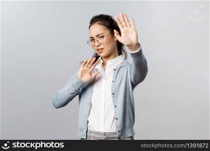 People, emotions and lifestyle concept. Portrait of displeased and disgusted asian woman defending herself from someone coughing close to her, turn away and raise hands from glimmering light.. People, emotions and lifestyle concept. Portrait of displeased and disgusted asian woman defending herself from someone coughing close to her, turn away and raise hands from glimmering light