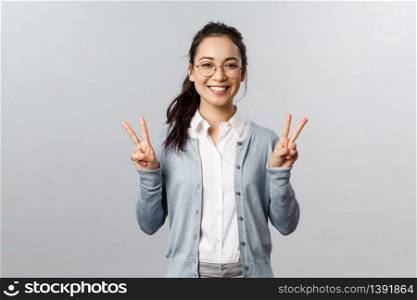 People, emotions and lifestyle concept. Staying on bright side. Cheerful smiling asian girl in glasses, showing peace signs kawaii, standing grey background friendly and rejoicing.. People, emotions and lifestyle concept. Staying on bright side. Cheerful smiling asian girl in glasses, showing peace signs kawaii, standing grey background friendly and rejoicing