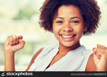 people, emotions, gesture and success concept - happy african american young woman with raised fists