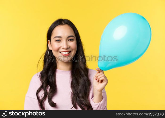 People emotions, lifestyle leisure and beauty concept. Cute smiling asian girl holding blue balloon as congratulating with big event, standing yellow background, through up surprise party.. People emotions, lifestyle leisure and beauty concept. Cute smiling asian girl holding blue balloon as congratulating with big event, standing yellow background, through up surprise party