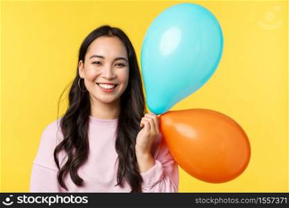 People emotions, lifestyle leisure and beauty concept. Smiling pretty asian girl with balloons smiling camera cheerful, celebrating holidays or big event, have birthday party, yellow background.. People emotions, lifestyle leisure and beauty concept. Smiling pretty asian girl with balloons smiling camera cheerful, celebrating holidays or big event, have birthday party, yellow background