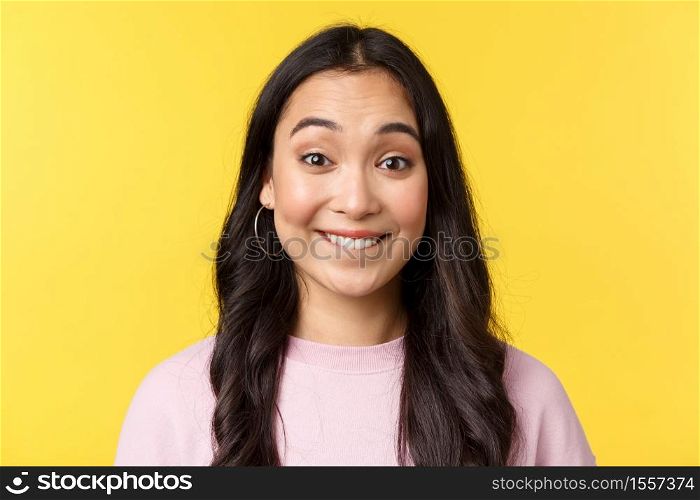 People emotions, lifestyle leisure and beauty concept. Upbeat happy asian girl anticipating big event or surprise, biting lip tempting see, standing yellow background excited.. People emotions, lifestyle leisure and beauty concept. Upbeat happy asian girl anticipating big event or surprise, biting lip tempting see, standing yellow background excited
