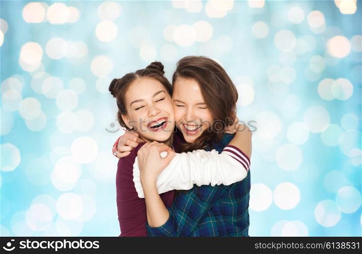 people, emotions, teens and friendship concept - happy smiling pretty teenage girls hugging and laughing over blue holidays lights background
