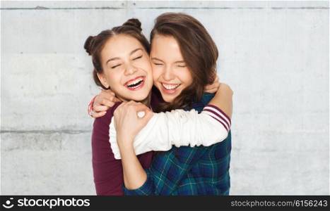 people, emotions, teens and friendship concept - happy smiling pretty teenage girls hugging and laughing over gray concrete wall background
