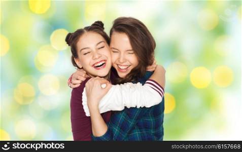 people, emotions, teens and friendship concept - happy smiling pretty teenage girls hugging and laughing over green holidays lights background