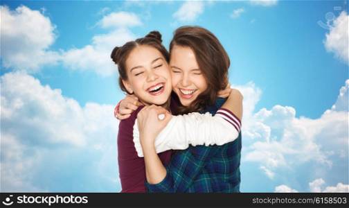 people, emotions, teens and friendship concept - happy smiling pretty teenage girls hugging and laughing over blue sky and clouds background