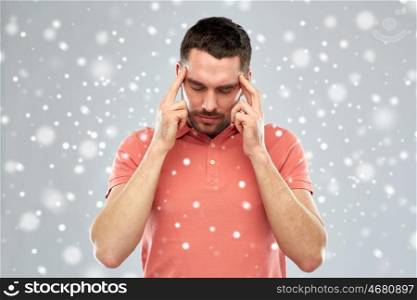 people, emotions, winter, christmas and stress concept - man suffering from head ache or thinking over snow on gray background