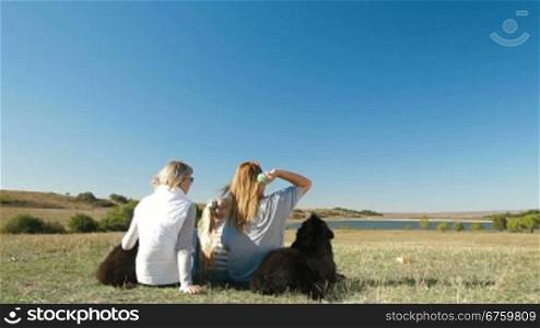 People enjoying in the nature with their Newfoundland dogs, rear view