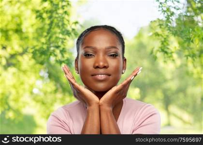 people, ethnicity and beauty concept - portrait of happy smiling african american young woman over green natural background. african american woman over natural background