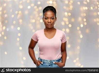 people, ethnicity and holidays concept - african american young woman over festive lights background. african american woman over lights background