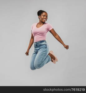 people, ethnicity and portrait concept - happy african american young woman jumping over grey background. happy african american woman jumping over grey