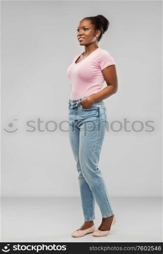 people, ethnicity and portrait concept - happy african american young woman over grey background. happy african american woman over grey background