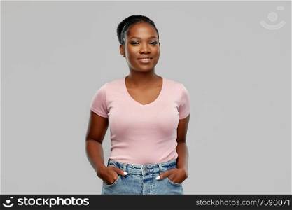 people, ethnicity and portrait concept - happy smiling african american young woman over grey background. happy african american woman over grey background