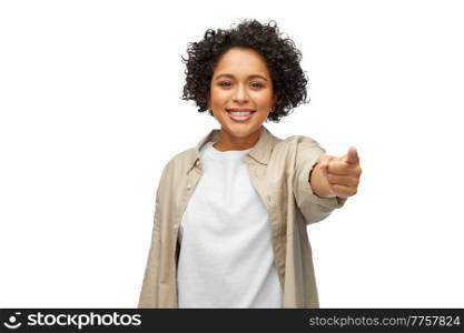 people, ethnicity and portrait concept - happy smiling woman in shirt pointing finger to camera over white background. portrait of happy woman pointing finger to camera