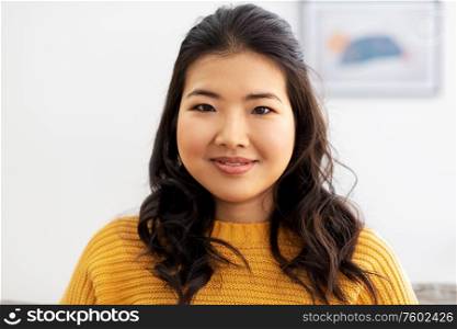 people, ethnicity and race concept - portrait of happy smiling asian young woman at home. portrait of happy smiling asian young woman
