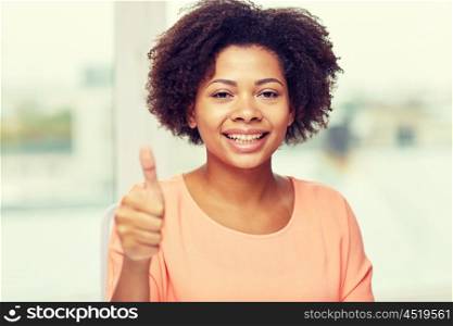 people, ethnicity, gesture and leisure concept - happy african american young woman showing thumbs up at home