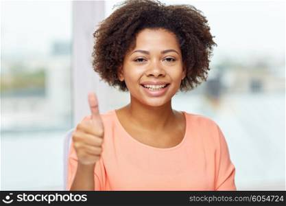 people, ethnicity, gesture and leisure concept - happy african american young woman showing thumbs up at home