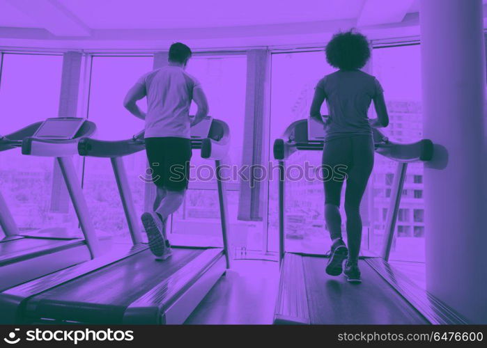 people exercisinng a cardio on treadmill in gym. young people exercisinng a cardio on treadmill running chine in modern gym duo tone filter