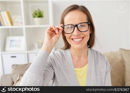 people, eyesight and vision concept - happy smiling middle-aged woman in eyeglasses at home. happy smiling woman in eyeglasses at home