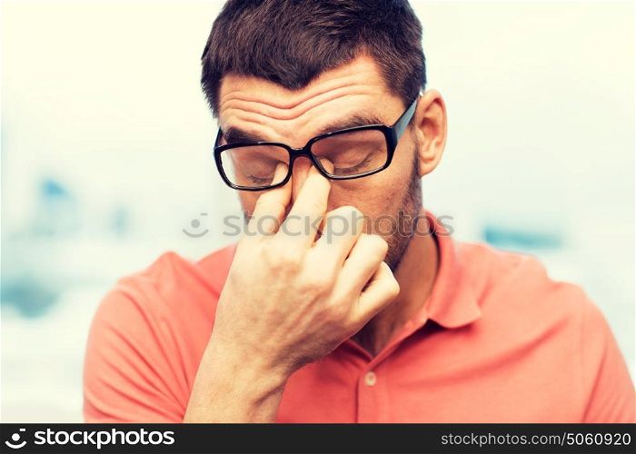 people, eyesight, stress, overwork and business concept - tired man in eyeglasses rubbing his eyes at home or work. tired man in eyeglasses rubbing eyes at home