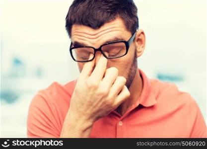 people, eyesight, stress, overwork and business concept - tired man in eyeglasses rubbing his eyes at home or work. tired man in eyeglasses rubbing eyes at home