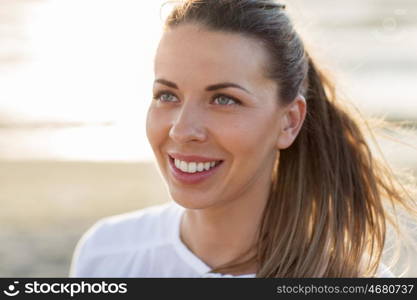 people, facial expression and emotion concept - happy young woman face on beach