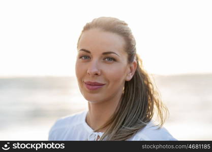 people, facial expression and emotion concept - happy young woman face on beach