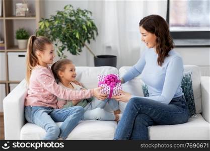 people, family and holidays concept - two daughters giving present to happy mother at home. daughters giving present to happy mother