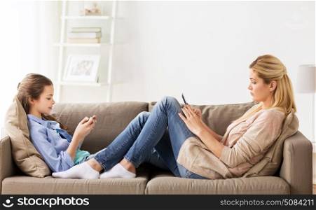 people, family and internet addiction concept - girl and mother with smartphones networking at home. family with smartphones networking at home. family with smartphones networking at home