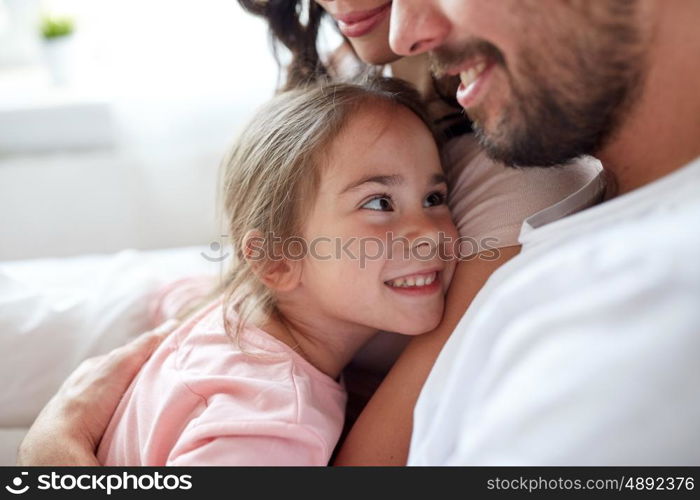 people, family and morning concept - close up of happy child with parents in bed at home
