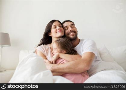 people, family and morning concept - happy child hugging parents in bed at home