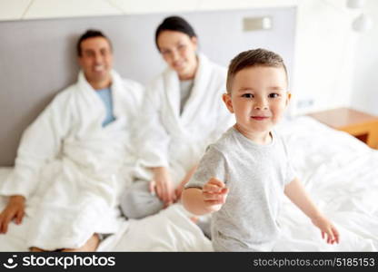 people, family and morning concept - happy child with parents in bed at home or hotel room. happy family in bed at home or hotel room