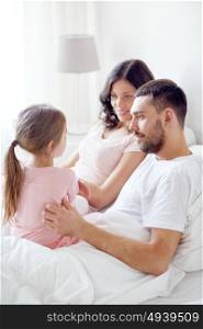 people, family and morning concept - happy child with parents in bed at home. happy family in bed at home