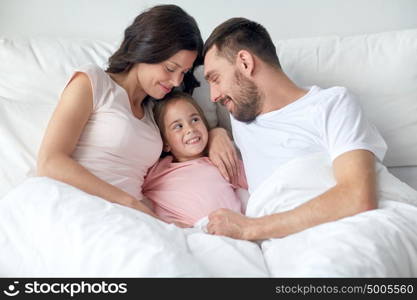 people, family and morning concept - happy child with parents in bed at home. happy family in bed at home
