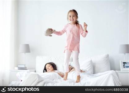 people, family and morning concept - happy child with toy and parents in bed at home
