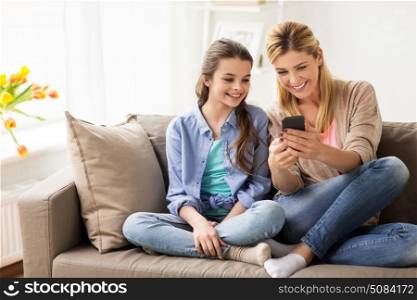 people, family and technology concept - happy girl and mother with smartphone at home. happy family with smartphone at home. happy family with smartphone at home
