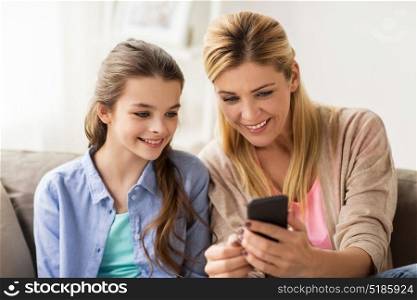 people, family and technology concept - happy girl and mother with smartphone at home. happy family with smartphone at home