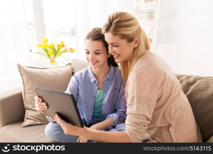 people, family and technology concept - happy girl and mother with tablet pc computer at home. happy family with tablet pc at home