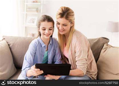 people, family and technology concept - happy girl and mother with tablet pc computer at home. happy family with tablet pc at home