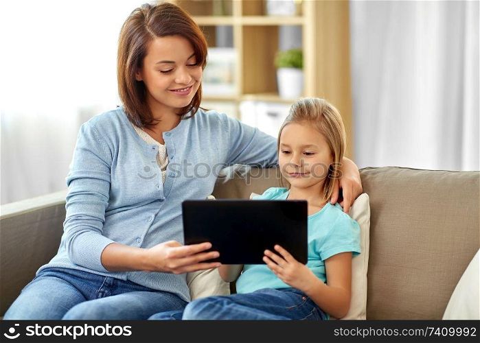 people, family and technology concept - happy mother and daughter with tablet pc computer at home. happy mother and daughter with tablet pc at home