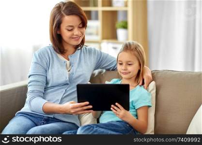 people, family and technology concept - happy mother and daughter with tablet pc computer at home. happy mother and daughter with tablet pc at home