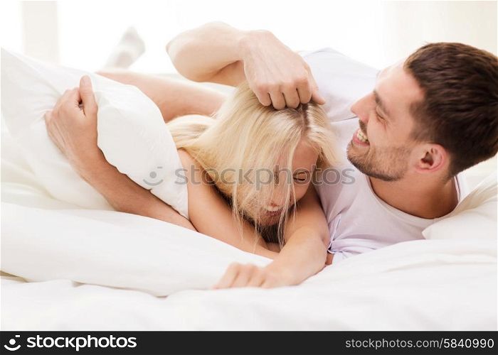 people, family, bedtime and happiness concept - happy couple having fun in bed at home
