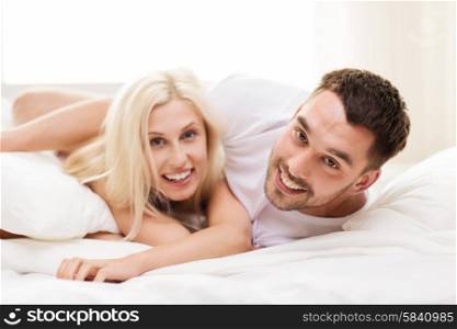 people, family, bedtime and happiness concept - happy couple lying in bed at home