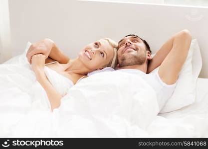 people, family, bedtime and happiness concept - happy couple lying in bed at home
