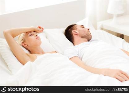 people, family, bedtime and insomnia concept - unhappy woman having sleepless night with sleeping man in bed at home