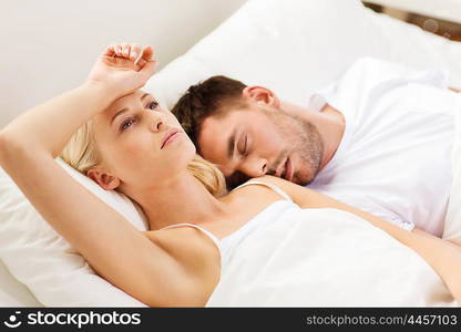 people, family, bedtime and insomnia concept - unhappy woman having sleepless night with sleeping and snoring man in bed at home