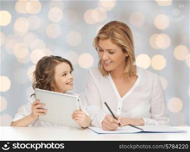 people, family, home education, children and technology concept - happy mother and daughter with tablet pc and notebook over holidays lights background