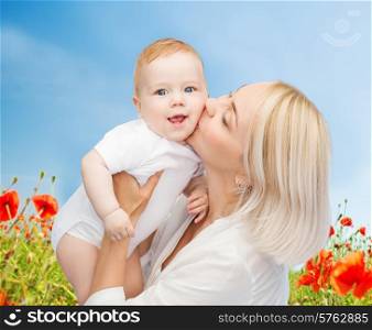 people, family, motherhood and children concept - happy mother hugging adorable baby over blue sky and poppy field background