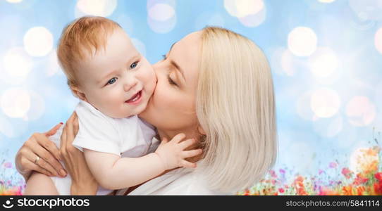 people, family, motherhood and children concept - happy mother hugging adorable baby over blue lights and poppy field background