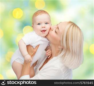 people, family, motherhood and children concept - happy mother hugging adorable baby over green lights background